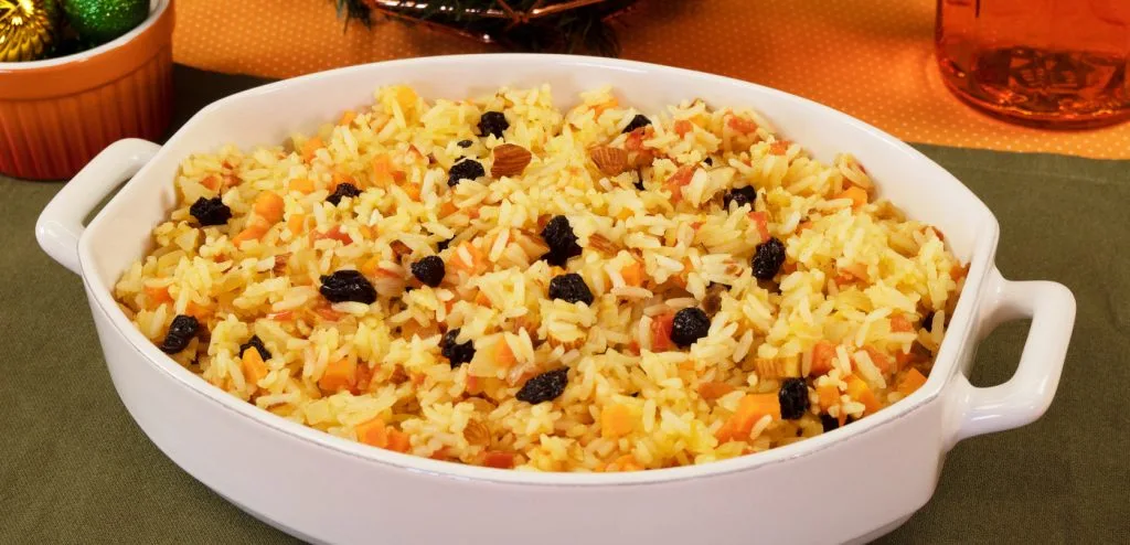 arroz de natal em um travessa branca sobre uma toalha verde 