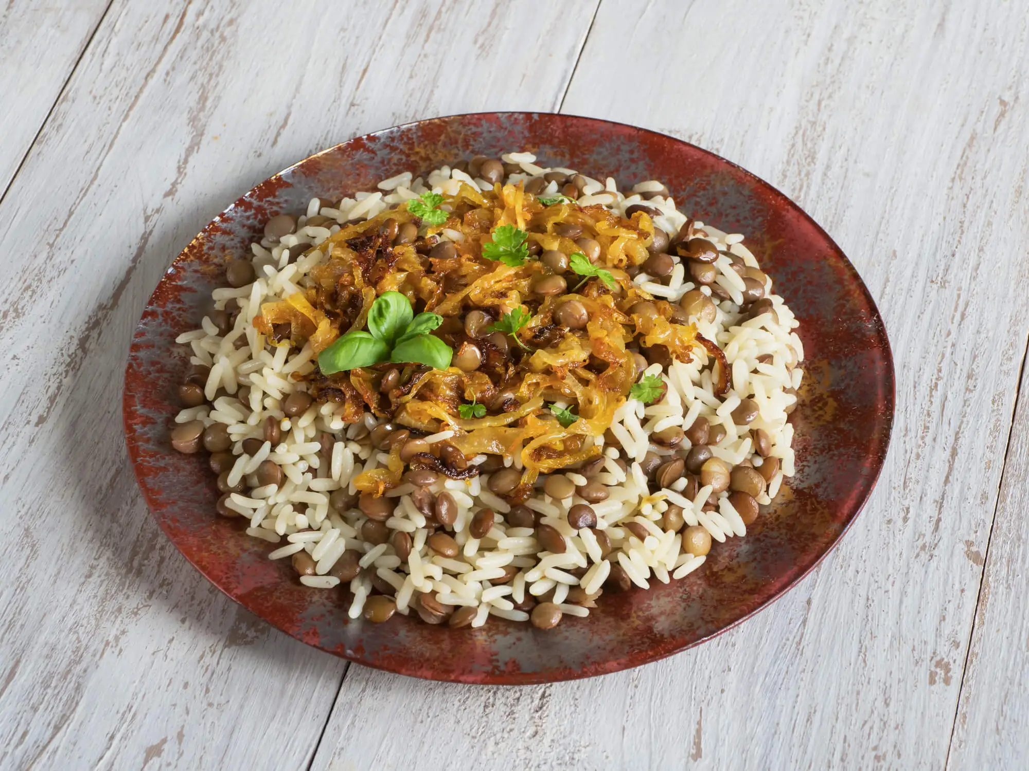 arroz com lentilha em um prato na cor marrom sobre uma mesa de madeira