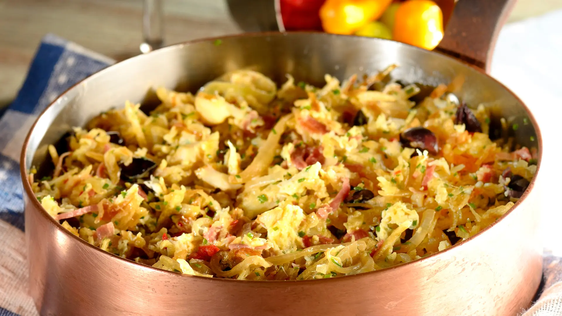 bacalhau em lascas em uma travessa de cobre ao fundo utensílios de cozinha