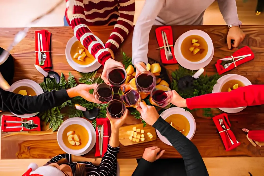 pessoas brindando com taças de vinho sobre uma mesa decorada com tema natalino