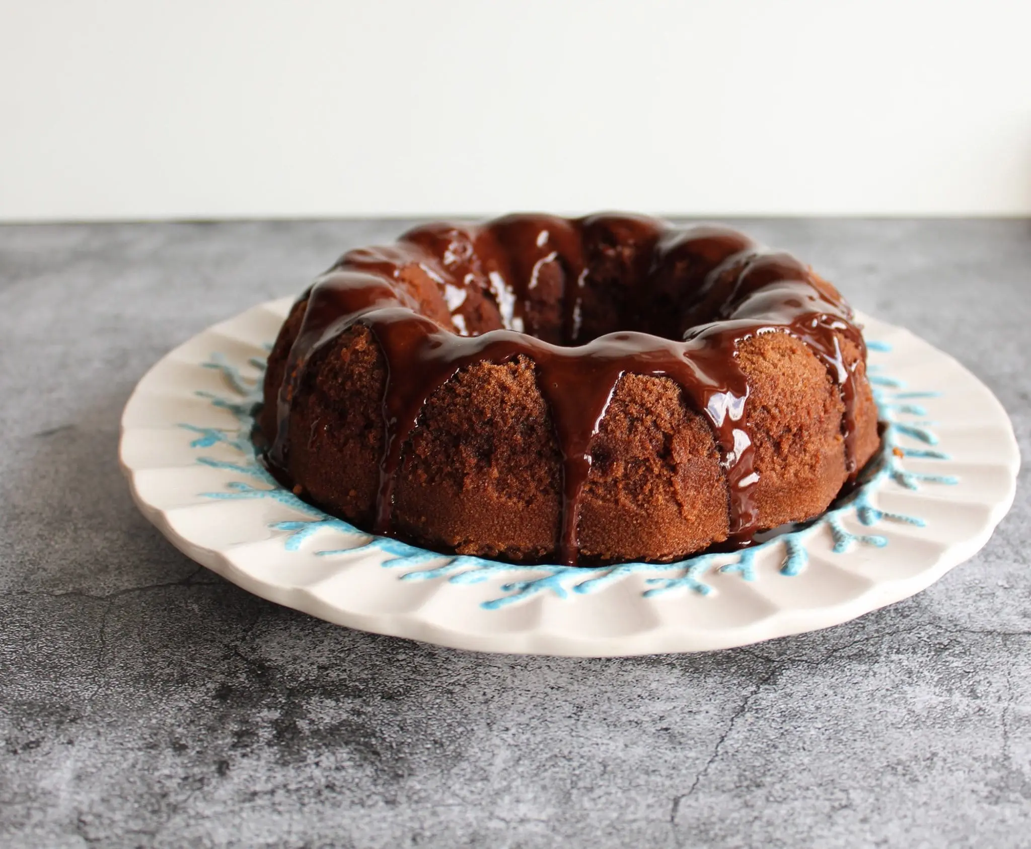 bolo de chocolate sobre uma prato branco e sobre uma mesa marmorizada