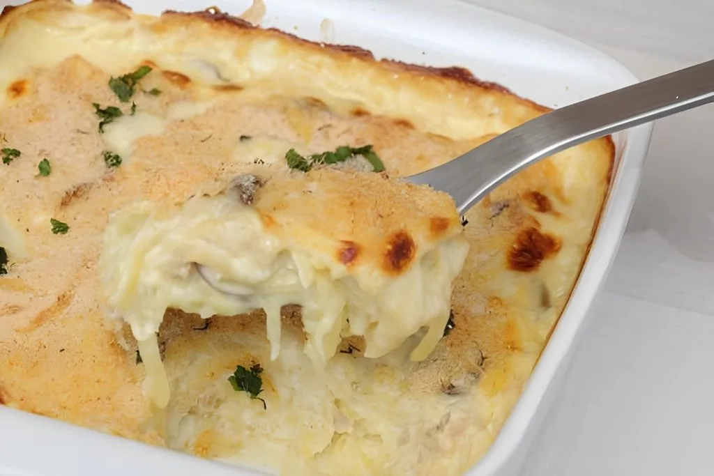 uma travessa com bacalhau com natas, uma colher retirando uma porção