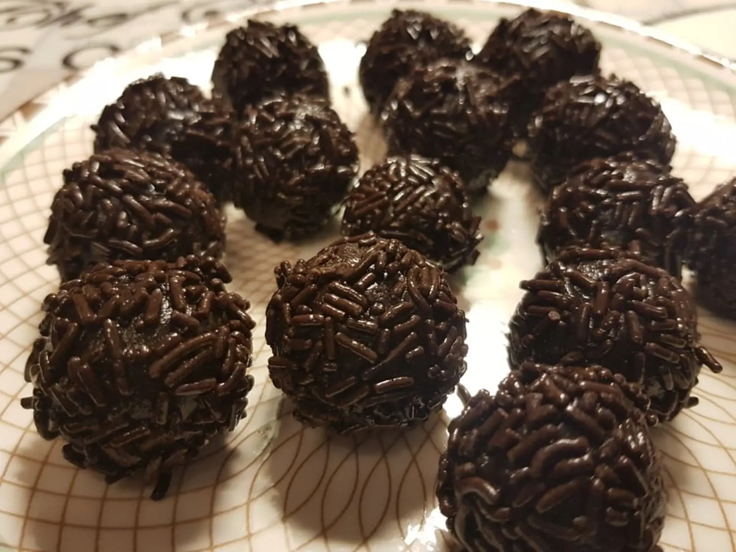 brigadeiros enrolados sobre um prato transparente