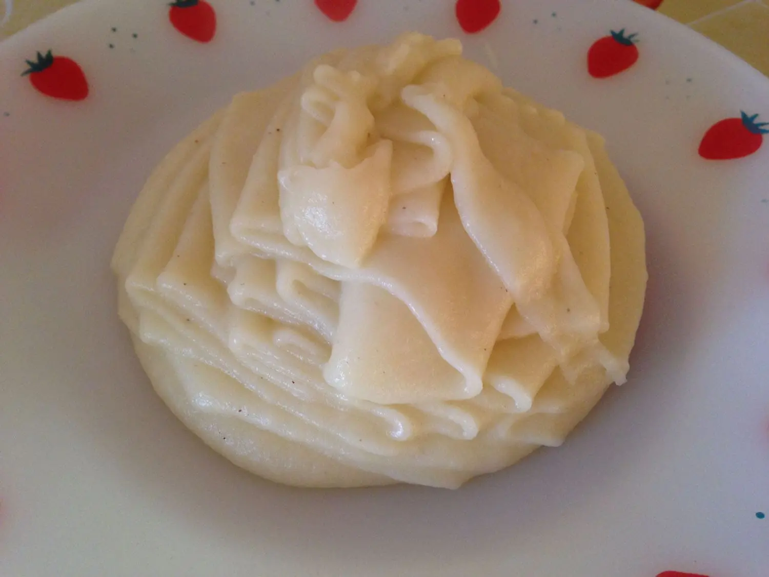 purê de batatas em um prato branco com desenho de morangos