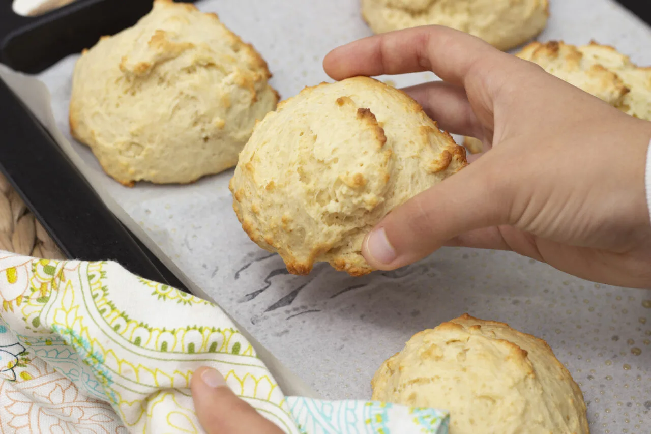 uma mão retirando um scones do tabuleiro