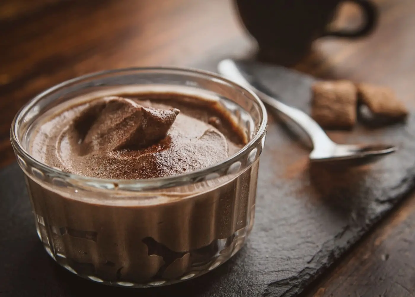 mousse de chocolate em um vasilha de sobremesa com uma colher ao lado sobre uma mesa de madeira