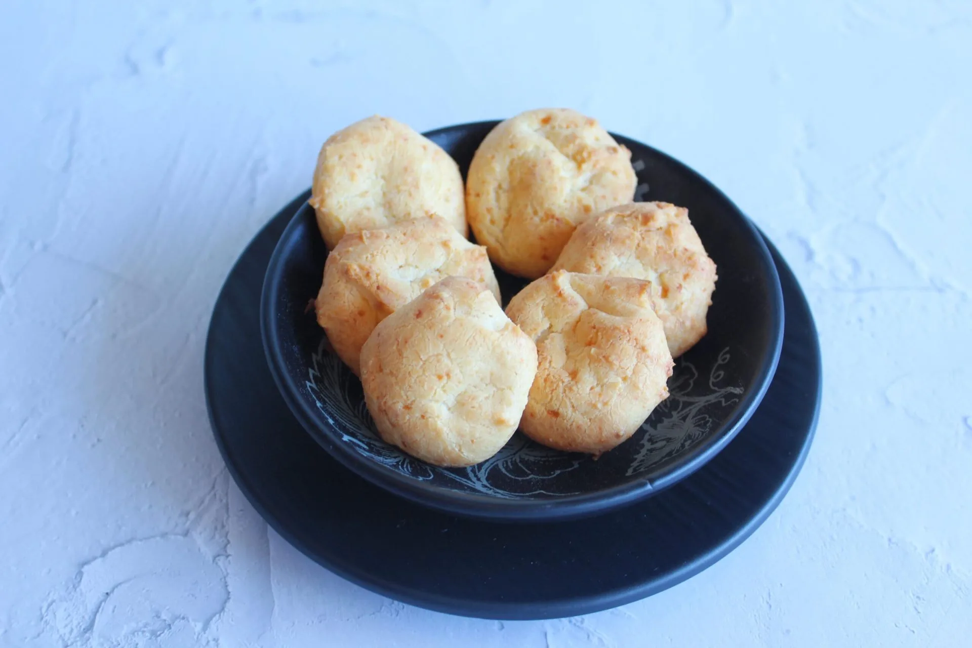 seis pães de queijo em um prato na cor preto