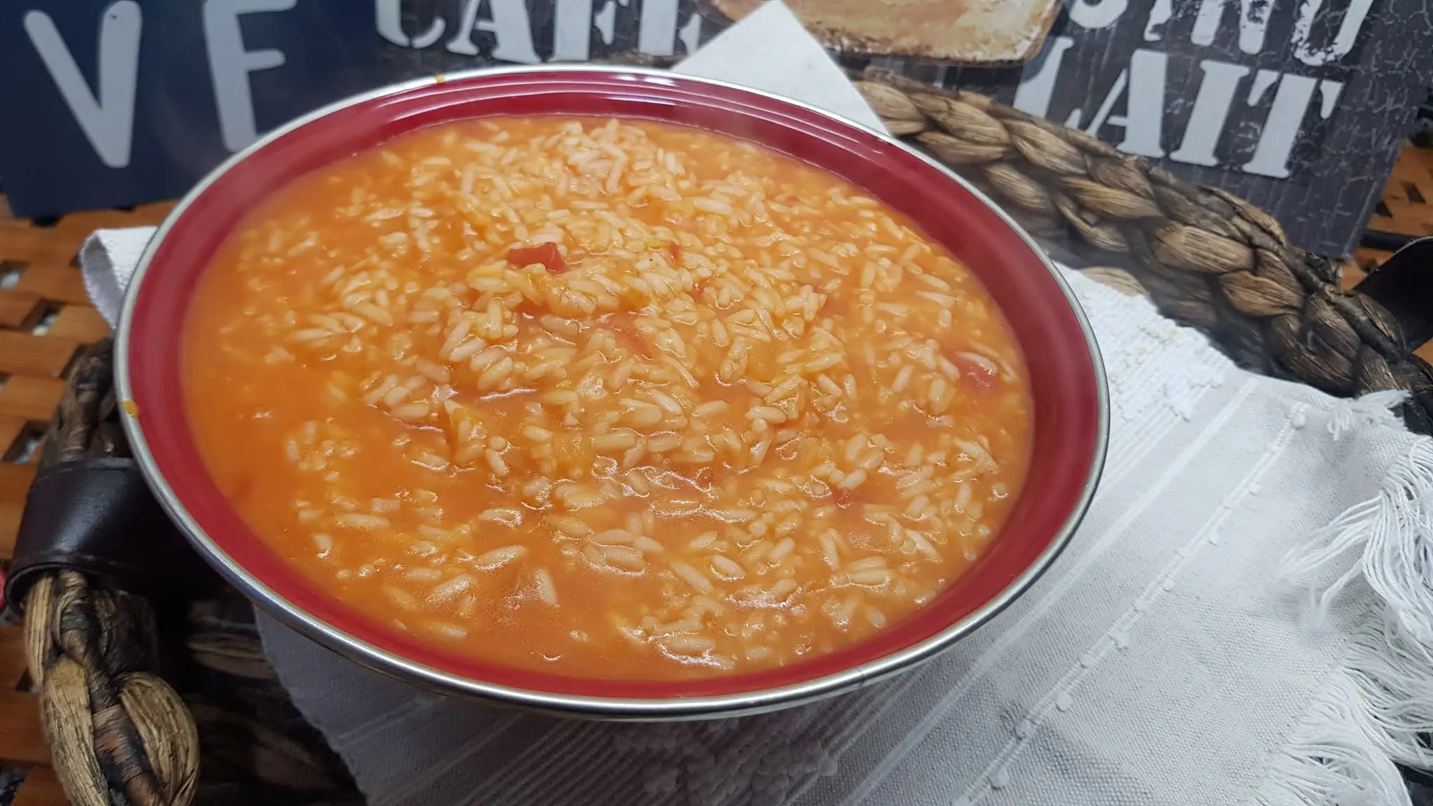 Arroz de tomate em um prato nas cores branco e vermelhos, sobre um guardanapo.