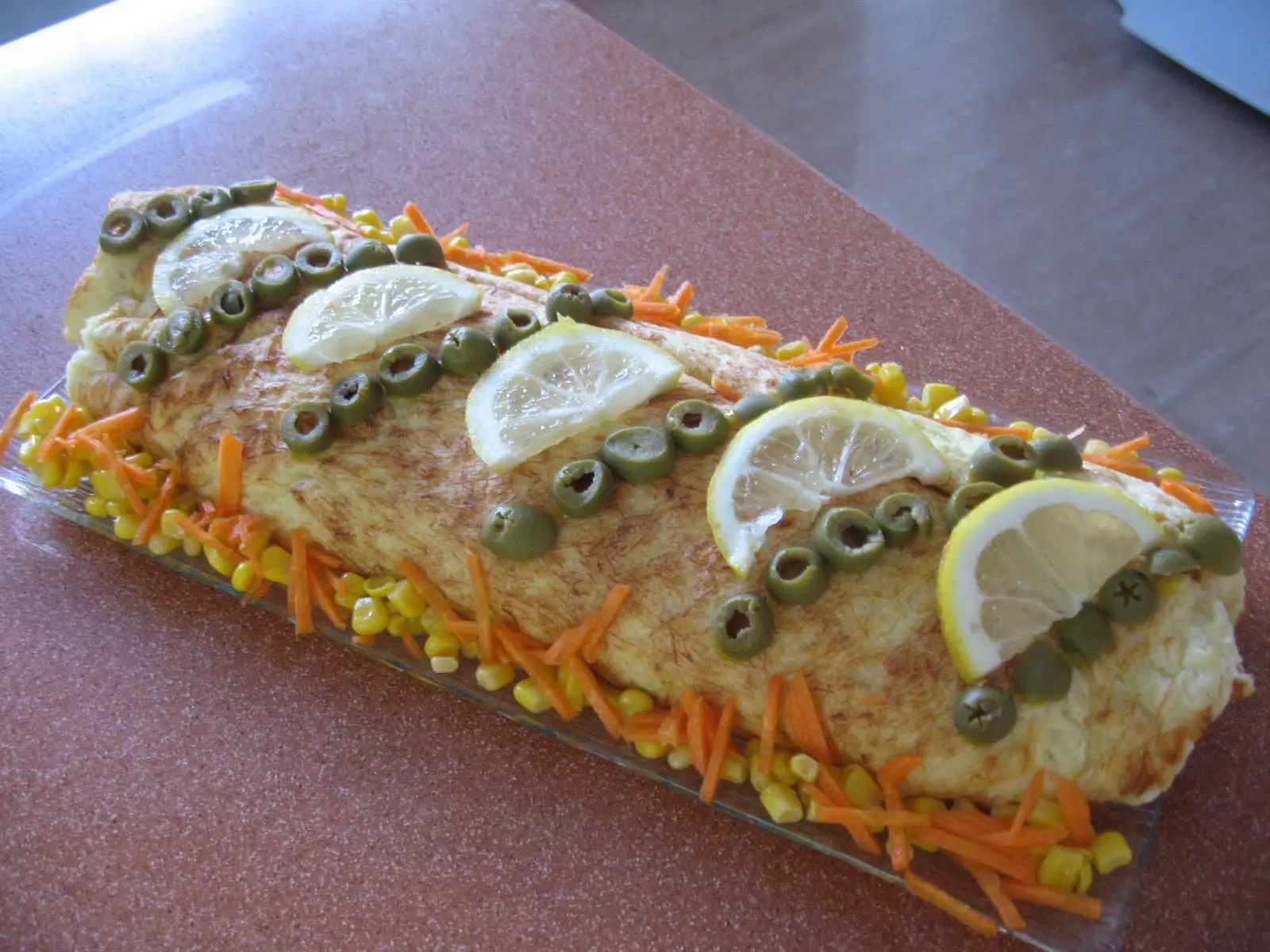 Torta de Bacalhau em formato de rolo sobre uma mesa de madeira