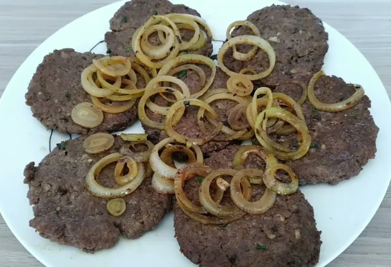 Bifes de carne moida em um prato branco com cebolas por cima