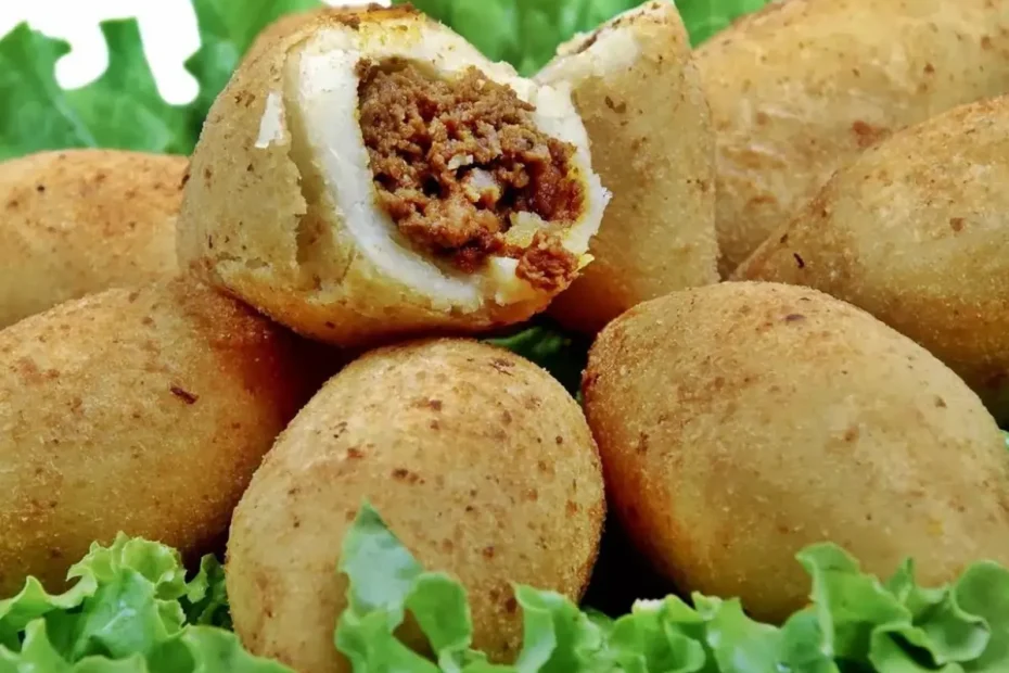 seis bolinho de mandioca com carne moida sobre folhas de alface.