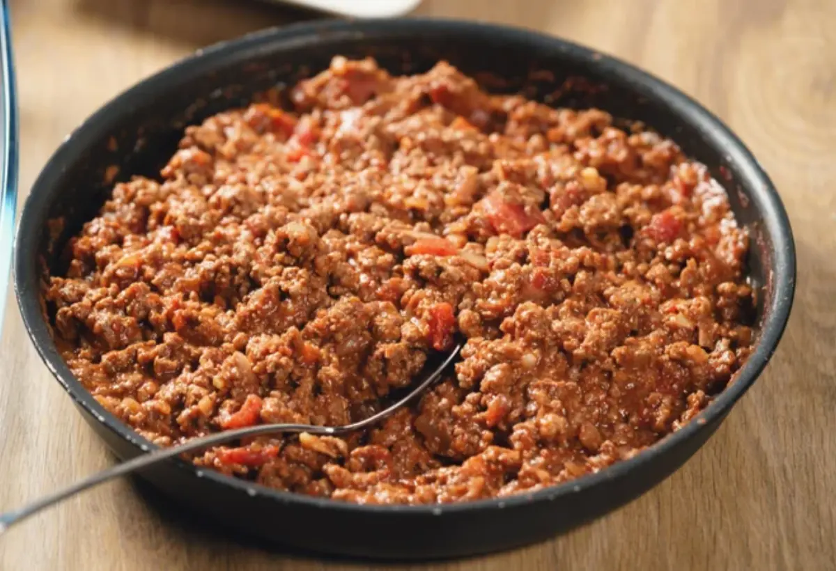 carne moída em uma tigela na cor preto sobre uma mesa de madeira