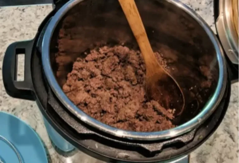 panela de pressão com carne moída, com uma colher de pau junto a carne