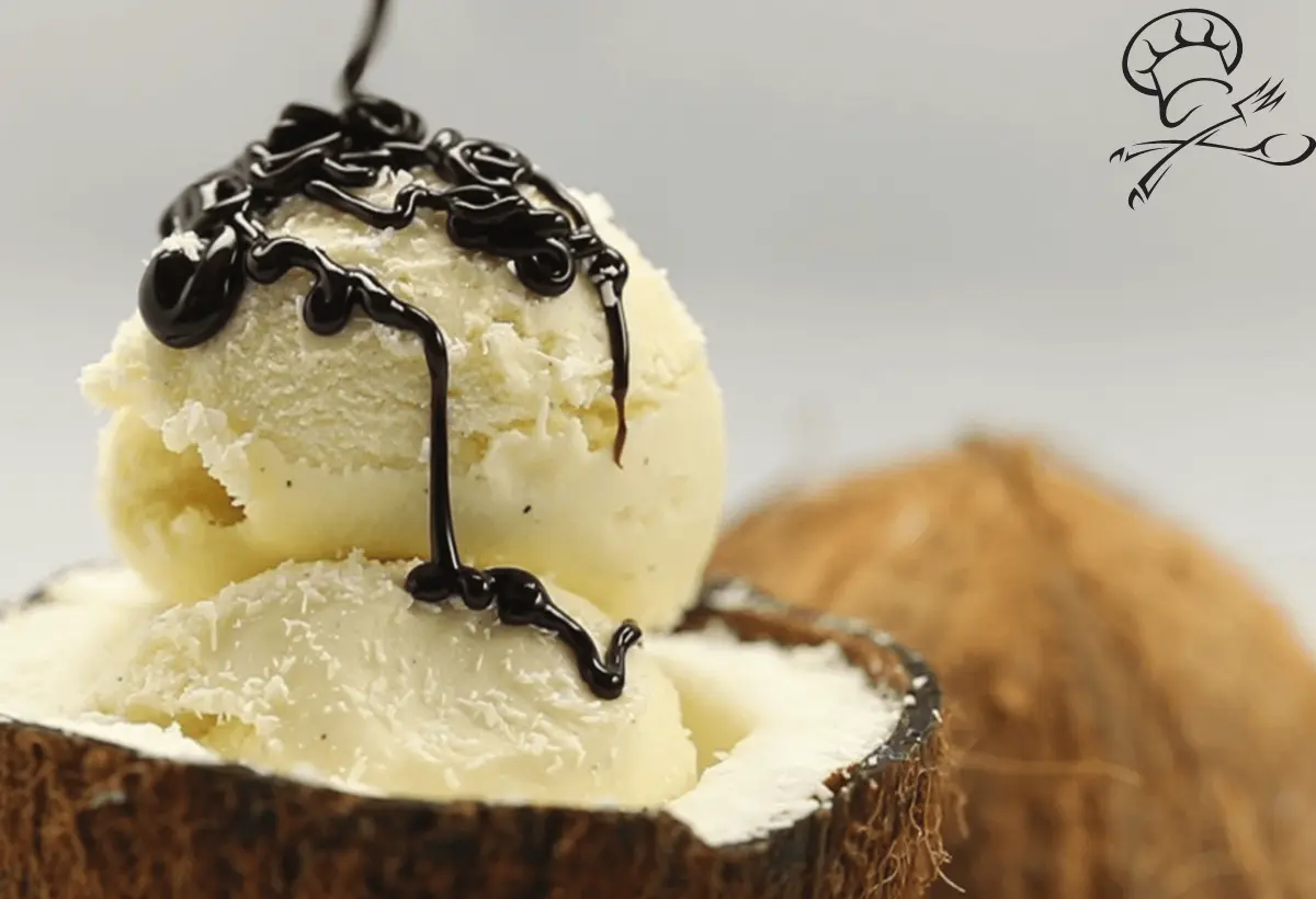 Duas bolas de gelado de coco dentro de um coco seco com cobertura de chocolate e ao fundo outro