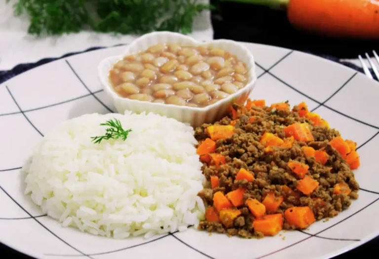 um prato com carne com cenoura, arroz e uma porção de feijão branco