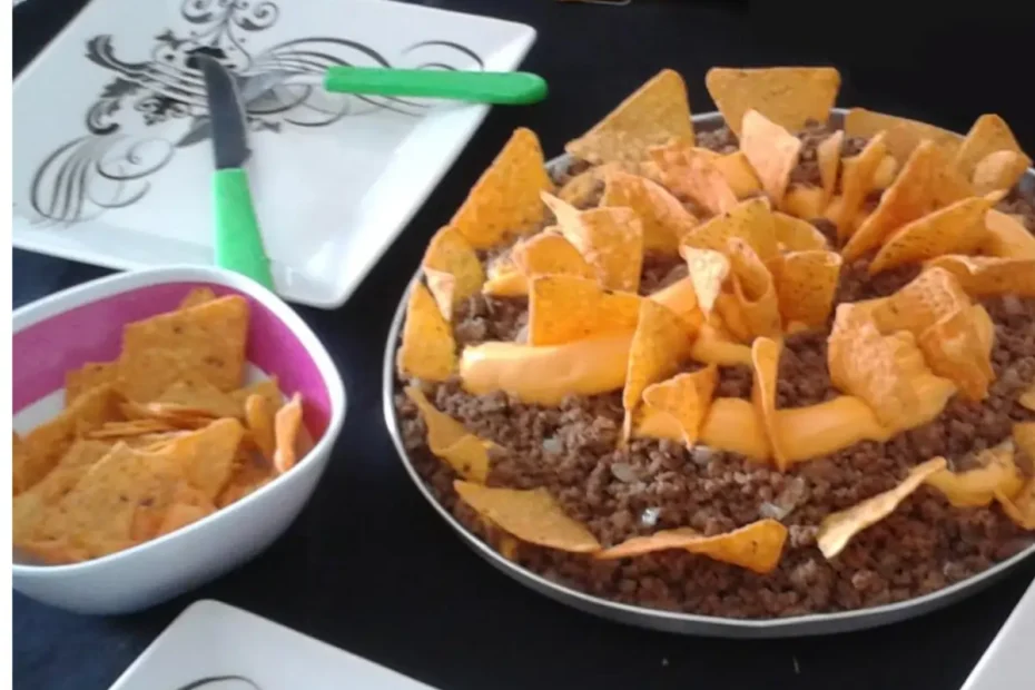 Doritos com carne moída em uma travessa, ao lado um prato na cor branca com desenhos em preto