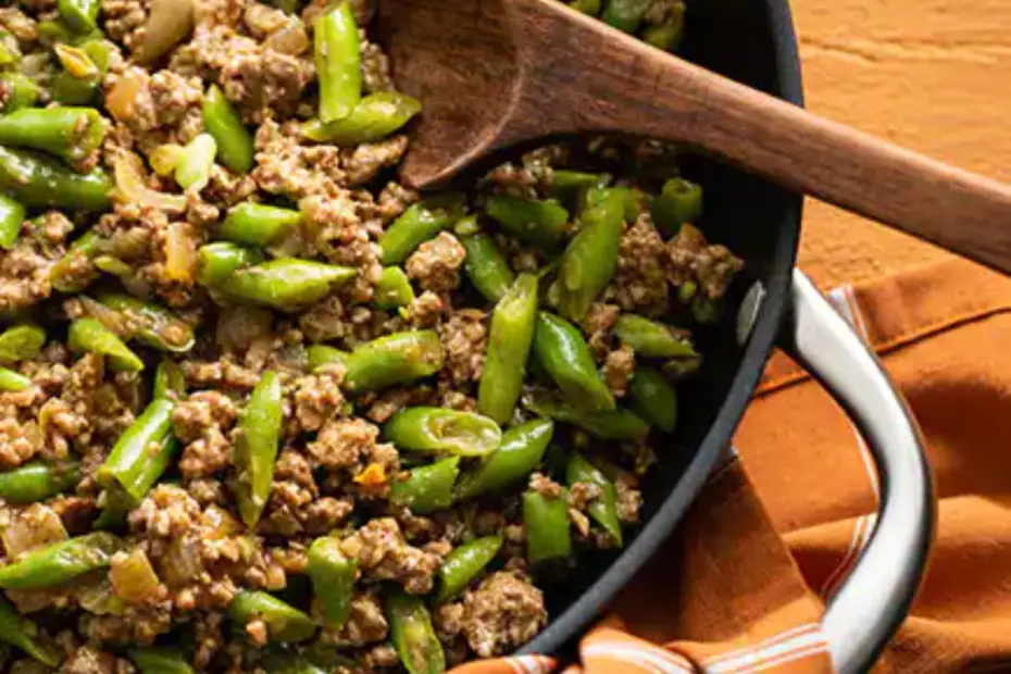 carne moída com vagem em uma panela com uma colher de pau