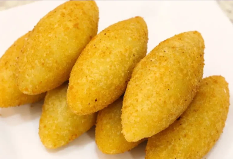 sete croquetes de mandioca com carne móida em um prato na cor branca