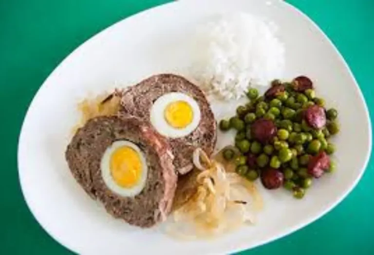 rolo de carne com ovo em um prato na cor branca, acompanhado por arroz e uma porção de ervilha