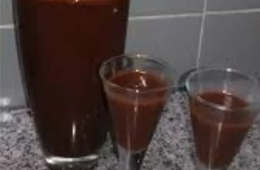 uma garrafa com duas taças pequenas na frente com licor de chocolate